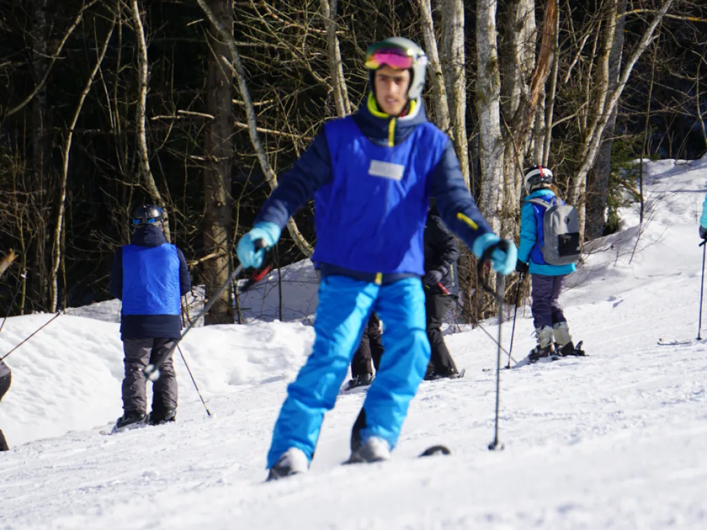 Jugendlicher steht in blauer Kleidung auf der Piste.